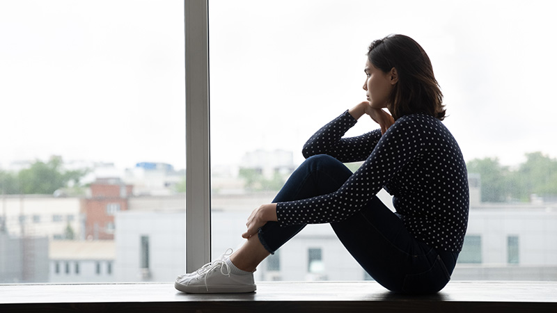 A woman struggling with an eating disorder looks outside a window.
