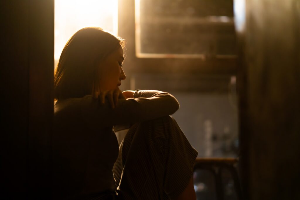 Woman holding herself while thinking about how does domestic violence affect women's mental health.